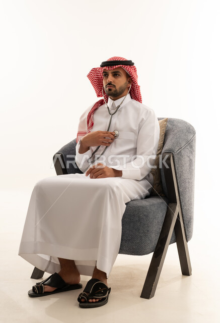 رجل سعودي بالثوب التقليدي يستخدم سماعة طبية