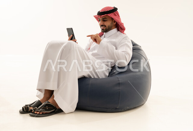 رجل سعودي بالثوب يستخدم الهاتف على بين باج