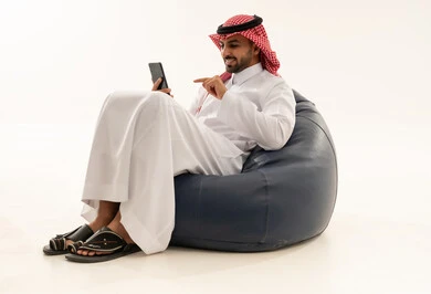 رجل سعودي بالثوب يستخدم الهاتف على بين باج