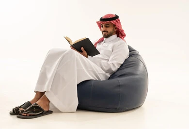 Saudi Man in Thobe Reading on Bean Bag