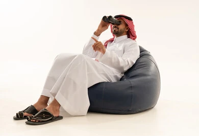 رجل سعودي بالثوب والشماغ يستخدم المنظار بخلفية بيضاء