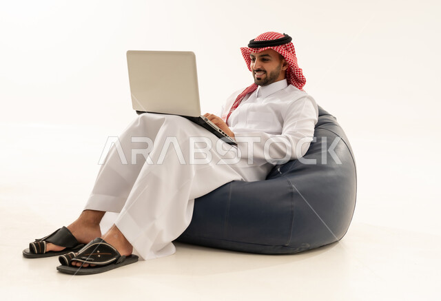 رجل سعودي يستخدم اللابتوب على كرسي بين باج