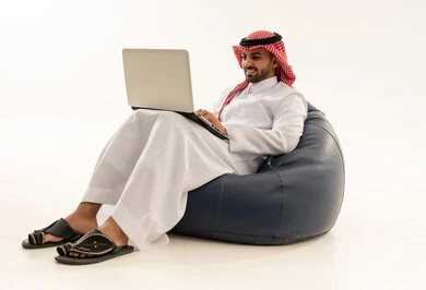 رجل سعودي يستخدم اللابتوب على كرسي بين باج