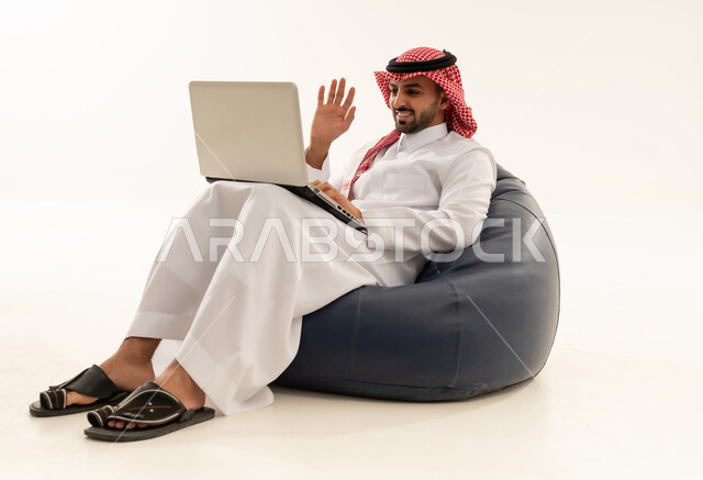 رجل سعودي يستخدم المحمول على مقعد مريح خلفية بيضاء