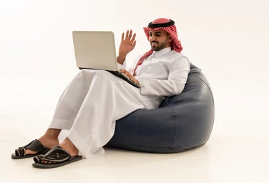 رجل سعودي يستخدم المحمول على مقعد مريح خلفية بيضاء