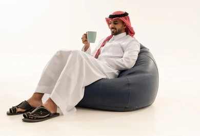 رجل سعودي بالثوب التقليدي يجلس على كرسي استرخاء