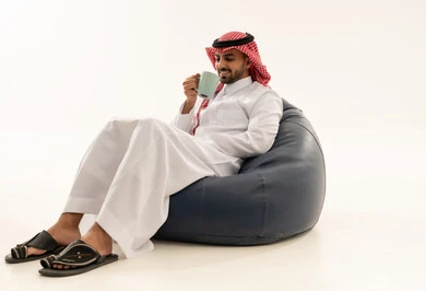 رجل سعودي بالثوب التقليدي يجلس على مقعد محشو