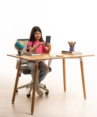 طفلة عربية تستخدم الهاتف الذكي على المكتب مع أدوات مدرسية