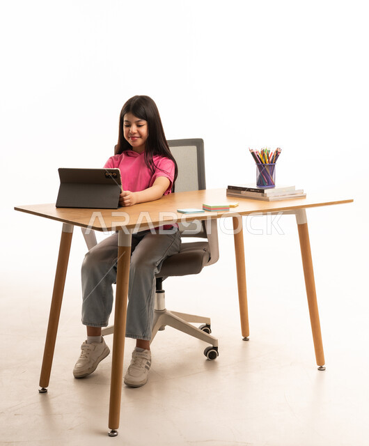 Saudi Girl Using Tablet at Desk in White Studio