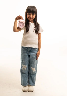 طفلة سعودية تمسك منبه وردي على خلفية بيضاء