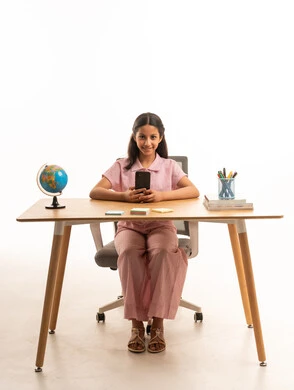 Saudi Girl at Desk Using Smartphone with School Supplies