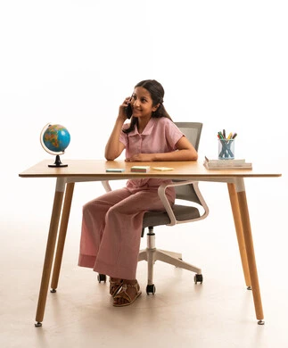 فتاة سعودية تتحدث بالهاتف على مكتب الدراسة