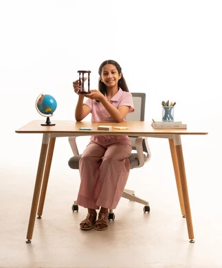 فتاة سعودية مع ساعة رملية على مكتب خشبي