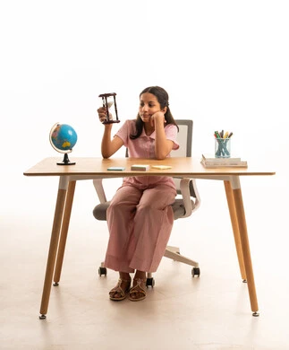 Saudi Girl with Hourglass at Desk on White Background