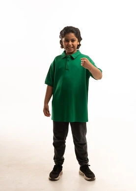 طفل عربي بقميص أخضر يقوم بعلامة النصر