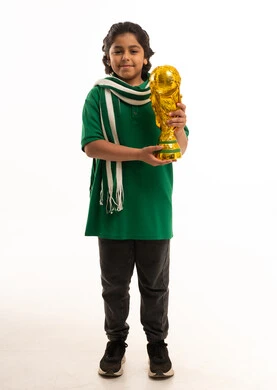 طفل سعودي يحمل كأس العالم على خلفية بيضاء