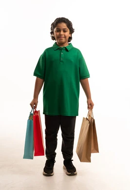 طفل عربي يحمل حقائب تسوق ملونة في الاستوديو