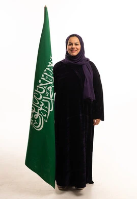 Saudi Woman in Abaya Standing with Saudi Arabia Flag