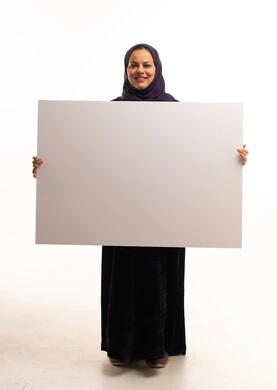 امرأة سعودية بالعباءة تحمل لوحة بيضاء فارغة