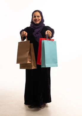 امرأة سعودية تحمل حقائب تسوق بخلفية بيضاء