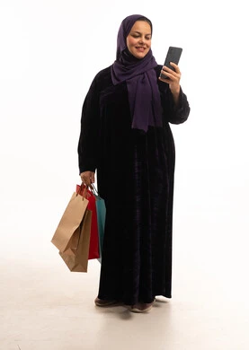 امرأة سعودية مع أكياس تسوق وهاتف ذكي