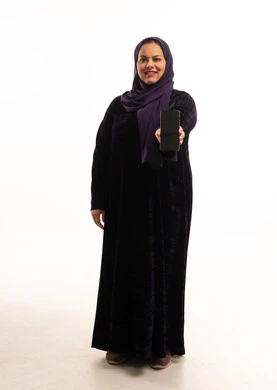 امرأة عربية بالعباية تمسك هاتف ذكي في الاستوديو