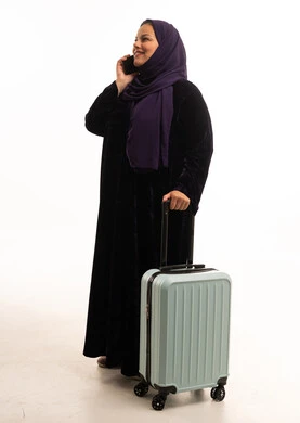 امرأة سعودية مع حقيبة سفر تتحدث بالهاتف في الاستوديو