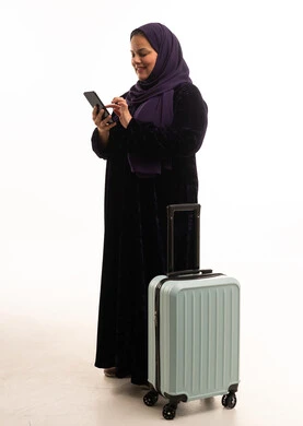 Saudi Woman with Suitcase Using Smartphone in Studio