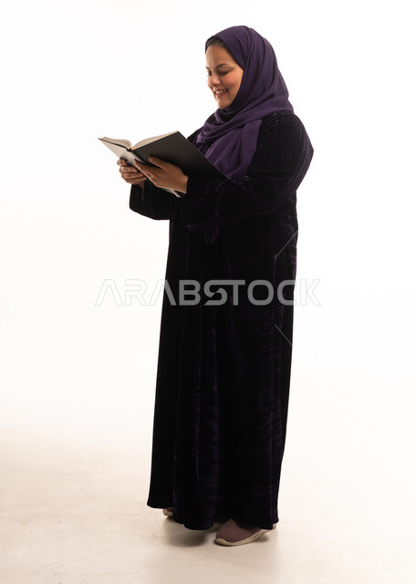 امرأة عربية تقرأ كتاباً بعباية سوداء وحجاب