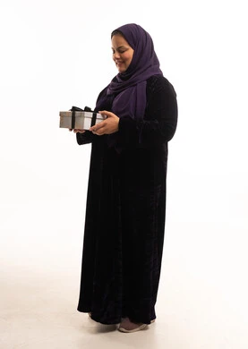 امرأة إماراتية بالعباية تحمل علبة هدايا