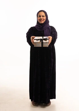 امرأة سعودية بالعباءة تحمل صندوق هدايا خلفية بيضاء