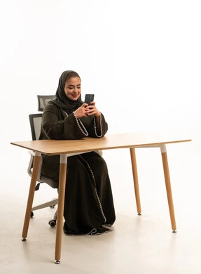 Emirati Woman in Abaya Using Smartphone at Desk