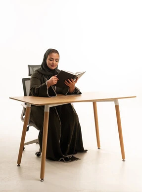 Saudi Woman in Abaya Reading Book at Desk