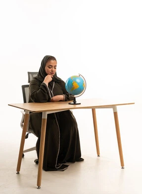 امرأة سعودية بالعباءة تنظر إلى الكرة الأرضية