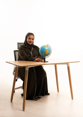 Saudi Woman in Abaya with Globe at Office Desk