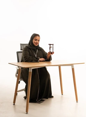 امرأة سعودية تمسك ساعة رملية في المكتب