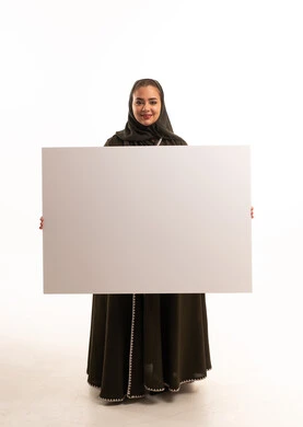 امرأة سعودية بالعباءة تحمل لوحة بيضاء فارغة