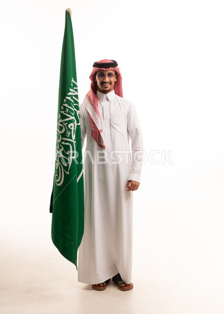 رجل سعودي يحمل علم السعودية بالثوب التقليدي