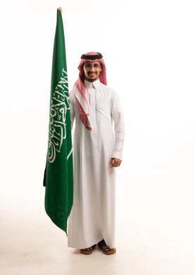 رجل سعودي يحمل علم السعودية بالثوب التقليدي