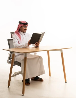 رجل سعودي بالزي التقليدي يقرأ على المكتب