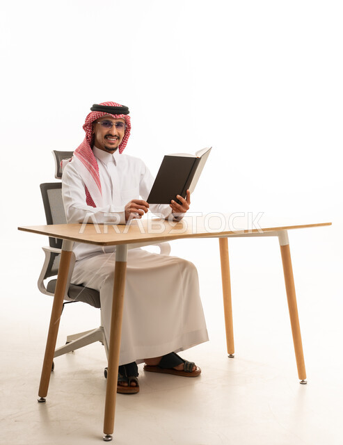 Saudi Man in Traditional Thobe Reading at Office Desk