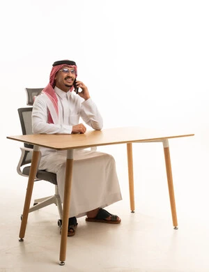 رجل أعمال سعودي يتحدث بالهاتف خلف المكتب