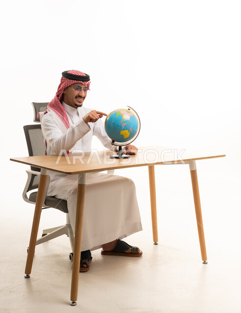 Saudi Man in Traditional Thobe Pointing at Globe