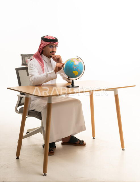 رجل سعودي باللباس التقليدي مع مجسم الكرة الأرضية