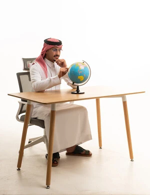 رجل سعودي باللباس التقليدي مع مجسم الكرة الأرضية