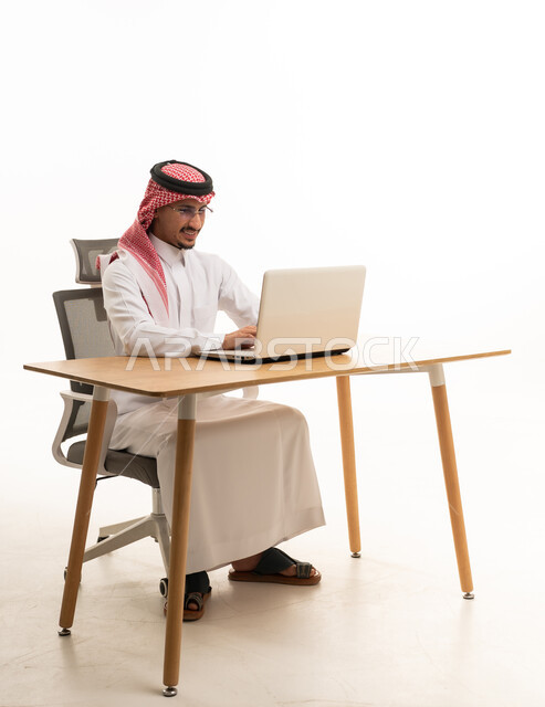 رجل سعودي بالثوب التقليدي يعمل على كمبيوتر محمول