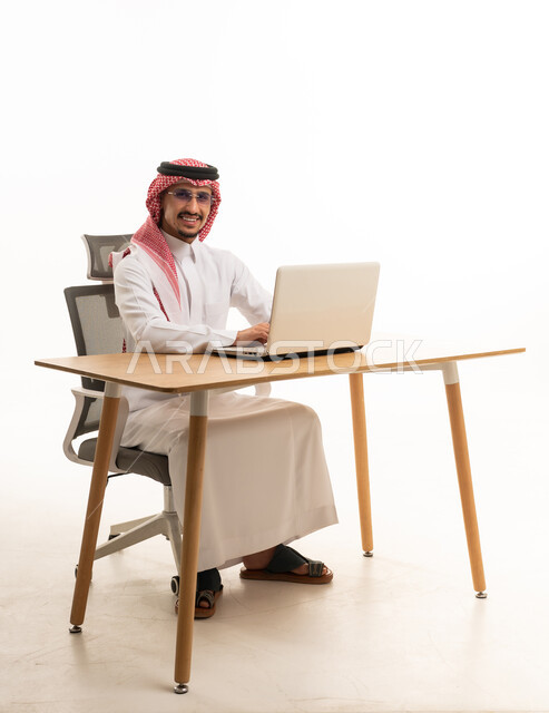 رجل أعمال سعودي يعمل على اللابتوب خلف مكتب