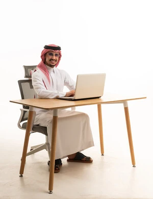 رجل أعمال سعودي يعمل على اللابتوب خلف مكتب