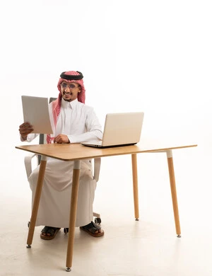 رجل أعمال سعودي مع كمبيوتر محمول ومستندات في المكتب