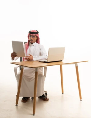 رجل سعودي مندهش ينظر إلى ورقة خلف المكتب